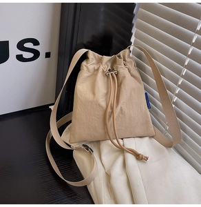 Close-up of khaki pleated nylon bucket bag showing drawstring closure and wide strap