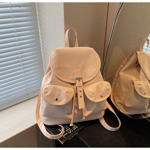 Detail of soft peach nylon backpack with double front pockets and magnetic silver buckles