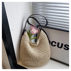 Detailed texture of the beige woven straw bucket bag with dark brown leather strap