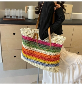 Macro detail of large woven tote bag featuring rainbow stripes and brown leather handles
