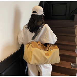 Rear view of a yellow large travel bag with brown leather handles and gray shoulder strap