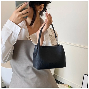 Détail d'un sac seau en cuir grainé noir avec logo embossé et poignée robuste
