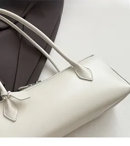 Close-up of minimalist creamy white baguette bag showing smooth faux leather and stitching