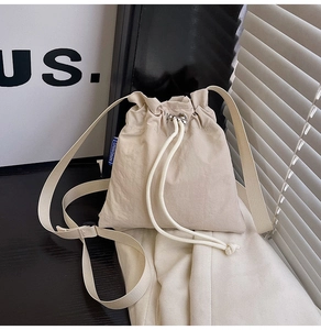 Detail of cream beige nylon bucket bag featuring a drawstring closure and silver eyelets