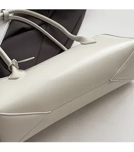 Close-up of precise stitching craftsmanship on the side and bottom of the cream leather bag