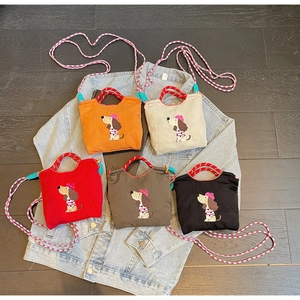 Five colorful crossbody bags with dog embroidery displayed on a denim jacket surface