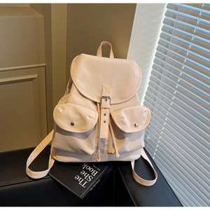 Detail view of cream canvas backpack featuring flap metal buckles and front magnetic pockets