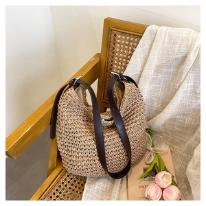 Detailed close-up of handmade woven straw bag texture and brown leather shoulder strap