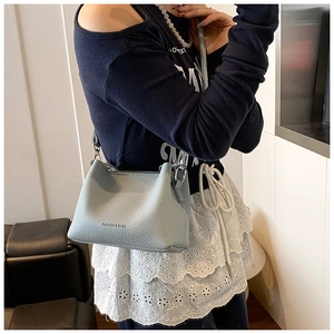 Détail du sac seau bleu clair avec texture cuir grainé et boucle argentée