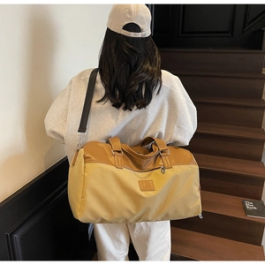 Detailed back view of a khaki canvas travel bag with leather trim on wood stairs