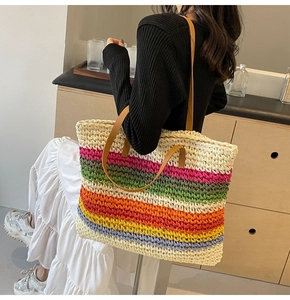 Detailed view of colorful rainbow straw tote bag with brown leather handles and woven texture