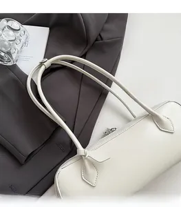 Detail of a cream baguette bag with bow-shaped stitching on long leather straps