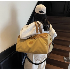 Close-up of yellow canvas travel bag with brown leather handles and side zip compartment