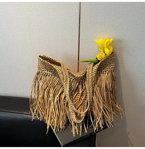 Close-up of beach straw tote bag featuring long decorative tassels and woven texture