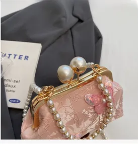 Détail du sac coquille en dentelle rose avec poignée en perles et sequins papillon brillants