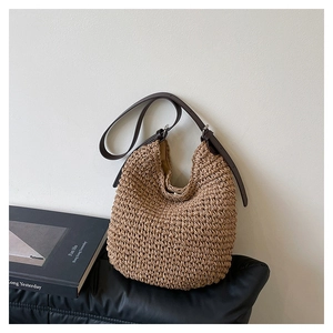 Detailed close-up of straw woven texture and brown leather strap with silver metal buckle