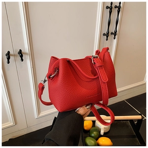 Gros plan d'un sac seau en cuir grainé rouge vif avec des boucles en métal argenté