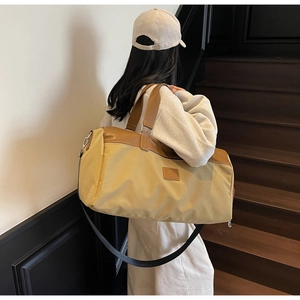Detail of khaki canvas travel bag featuring brown leather trim and detachable shoulder strap