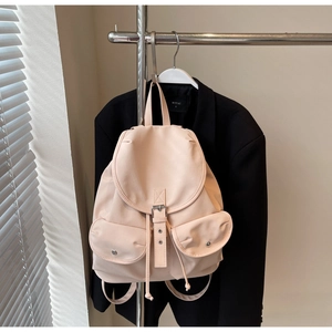 Detail of nude pink backpack with drawstring closure, flap design, and silver buckles