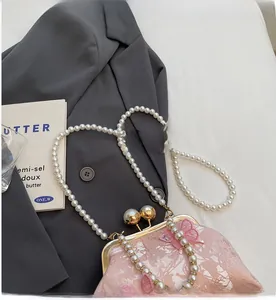 Détail du sac en tissu rose avec broderie papillon et bandoulière en perles