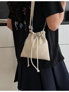 Minimalist beige drawstring nylon bucket bag with adjustable strap for travel and leisure