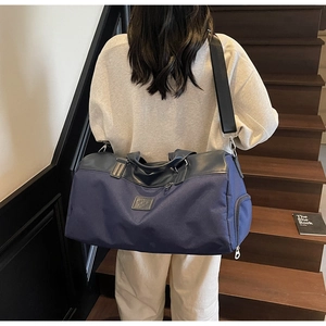 Detail view of the deep blue travel bag showing the waterproof nylon fabric and leather handle