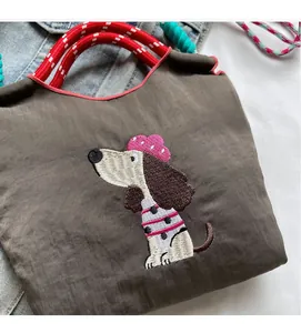 Detailed close-up of cartoon dog embroidery and woven rope handle on brown canvas bag