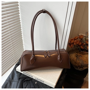 Detailed macro view of the smooth brown leather texture and dual silver zipper on the bag