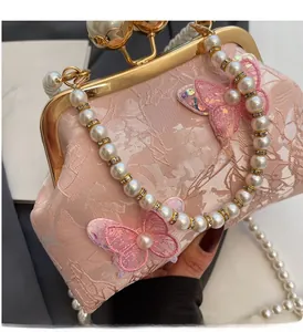 Détail du sac coquille en jacquard rose avec papillons à paillettes et anse en perles