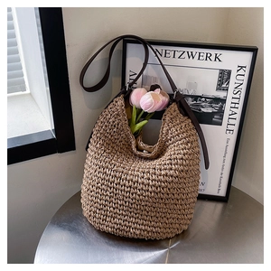 Detailed close-up of woven straw tote bag featuring brown leather strap and pink tulips