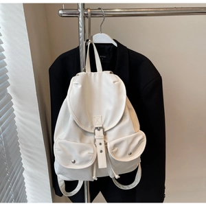 Detail view of white PU leather backpack featuring dual snap pockets and flap closure