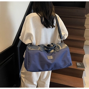 Detail view of large navy nylon travel bag with leather accents and adjustable shoulder strap