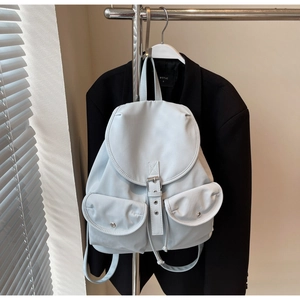 Detail view of a light gray backpack with metal buckles and flap pockets on a suit hanger