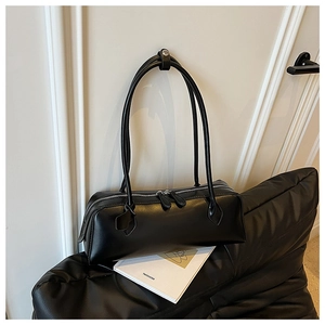 Close-up of a black leather rectangular baguette bag with minimalist double zip details