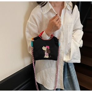 Detail of embroidered cartoon puppy on black canvas crossbody bag with woven straps