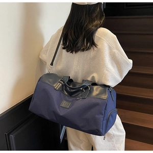 Detail of large navy canvas travel bag with leather accents and side zip compartment