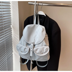 Minimalist light grey waterproof backpack with buckle details hanging on a metal rack