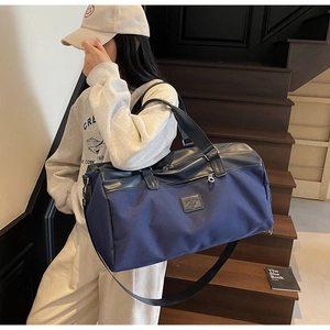 Large navy canvas travel bag with leather accents shown on a vintage staircase