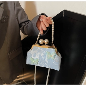 Détail du sac coquillage brodé bleu clair avec anse en perles et papillons en 3D