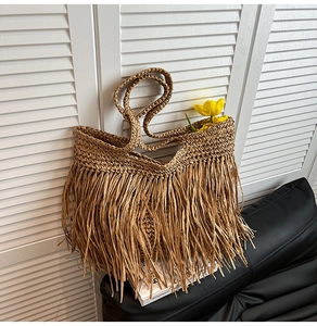 Detail of hand-woven straw tote bag with long tassels and bohemian fringe texture