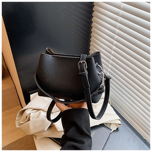 Détail d'un sac seau en cuir grainé noir avec ferrures argentées et logo embossé tendance