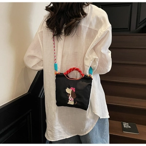 Detail of dachshund embroidery on black nylon shoulder bag with red woven handle