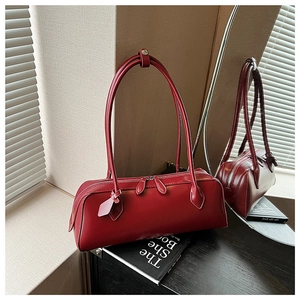 Detail of burgundy leather Boston bag showing glossy texture and slim shoulder straps