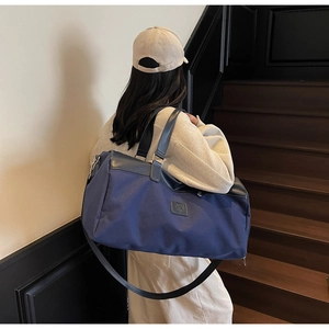 Close-up of large blue nylon travel bag with black leather handles and long shoulder strap
