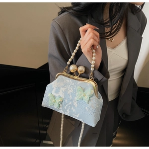 Détail du sac brodé floral bleu clair avec ornements papillons et chaîne en perles