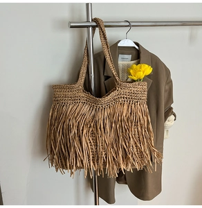 Detail of bohemian straw woven tote bag with long fringe tassels and a large capacity