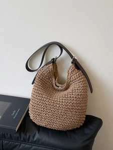 Woven straw bucket bag with adjustable leather strap and textured artisanal finish