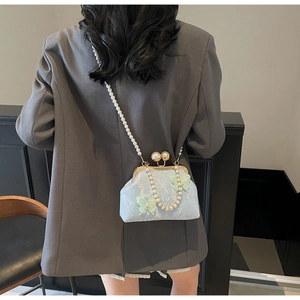 Détail d'un sac jacquard bleu avec papillons 3D et élégante poignée en perles
