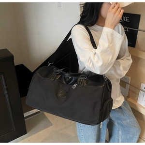 Detailed side view of black large-capacity travel bag with circular logo and shoe pocket