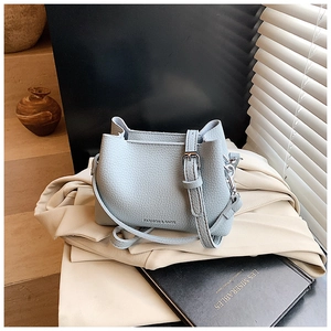 Gros plan d'un sac seau en cuir bleu clair à motif lychee avec des détails argentés